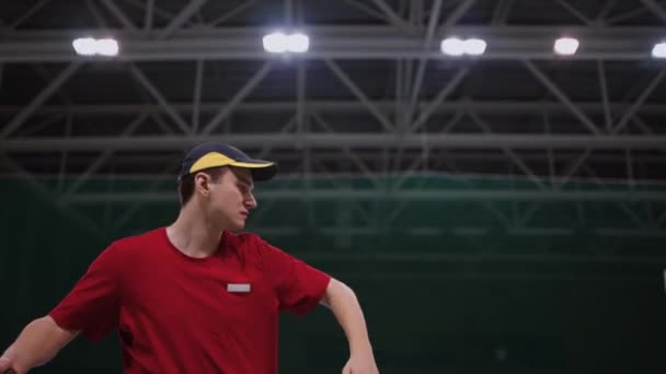 Aktywny młody człowiek gra w tenisa na korcie wewnątrz stadionu, aktywność sportowa i hobby, sportowiec z rakietą uderza piłkę — Wideo stockowe