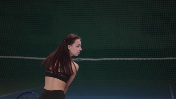 Pasatiempo deportivo de la joven jugadora de tenis, la deportista está entrenando en la cancha cubierta, corriendo y golpeando la pelota — Vídeos de Stock
