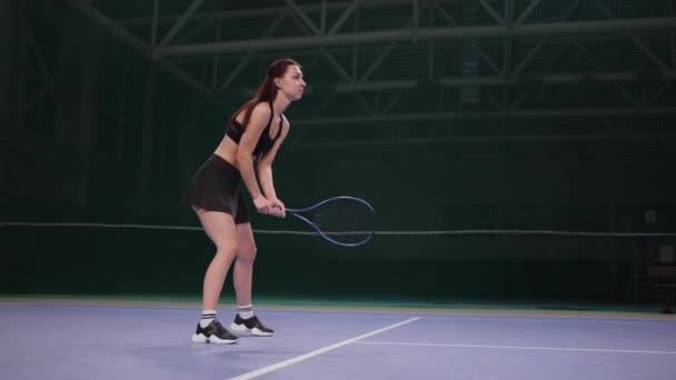 Ung tennisspelare kvinna tränar strejker på bollen, spela tennis på inomhus domstol, slow motion skott — Stockvideo