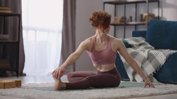 Stretching εκπαίδευση της ενήλικης γυναίκας στο σπίτι, γυναίκα αθλητής κάθεται στο πάτωμα, εκτελεί ασκήσεις για την ευελιξία — Αρχείο Βίντεο