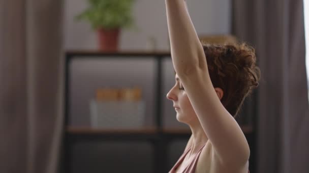 Hemma fitness koncept, vuxen dam sträcker kroppen sitter på golvet i rummet, hälsosam livsstil — Stockvideo