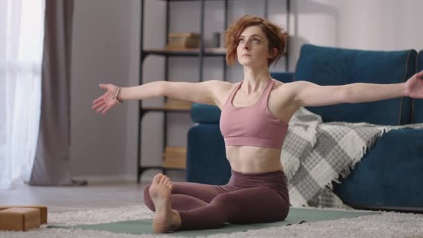 Ενήλικη κυρία κάνει ασκήσεις τεντώματος στο σπίτι, κάθεται στο πάτωμα στο σαλόνι, την ανάπτυξη της ευελιξίας — Αρχείο Βίντεο