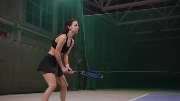 Joven jugadora de tenis está esperando huelga de oponente en pista de tenis, deportista está golpeando pelota — Vídeos de Stock