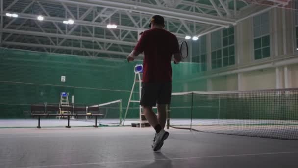 Dorosły mężczyzna tenisista trenuje sam na pustym korcie, ocieplenie i przygotowanie do zawodów, widok z tyłu — Wideo stockowe