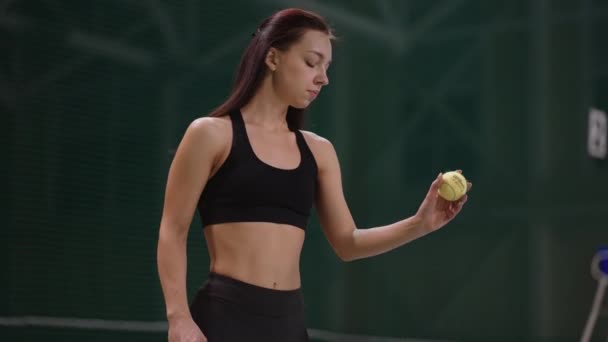 Kvinnlig tennisspelare värmer handen och serverar en boll på tennisbana, porträtt skott inomhus — Stockvideo