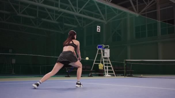 Ung atletisk kvinna med tennis racket spelar tennis på planen, kör och slå bollen, slow motion skott — Stockvideo