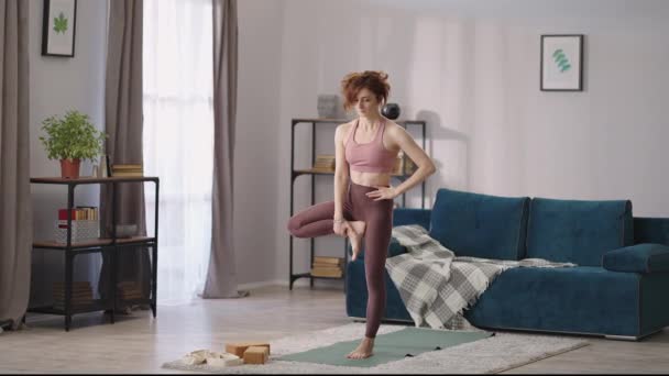 Femme fait de l'exercice pour l'équilibre, debout sur une jambe dans l'appartement, pratique du yoga, exercices pour une bonne condition physique — Video