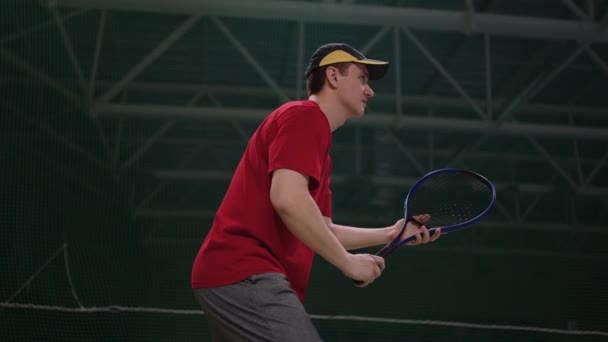 アクティブ男子テニス選手が相手の攻撃を撃退屋内コートのラケットでボールを打つ — ストック動画