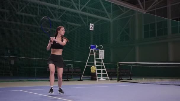 Framtida kvinnliga mästare i tennis är träning på inomhus domstol, förbereder sig för konkurrens, full längd slow motion — Stockvideo