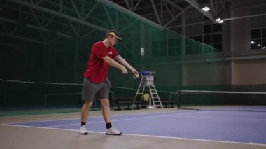 Tenisçi servis yapmayı öğreniyor, kapalı tenis kortunda tam boy portre, raket eğitimi ve alıştırma grevleri