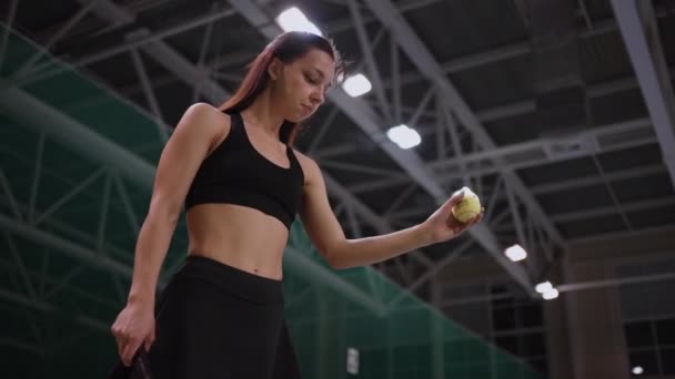 Νεαρή αθλήτρια σε κλειστό γήπεδο τένις, παίζει με μπάλα πριν το σερβίρισμα, ξεκινώντας σπορ αγώνα, πορτρέτο πυροβόλησε — Αρχείο Βίντεο
