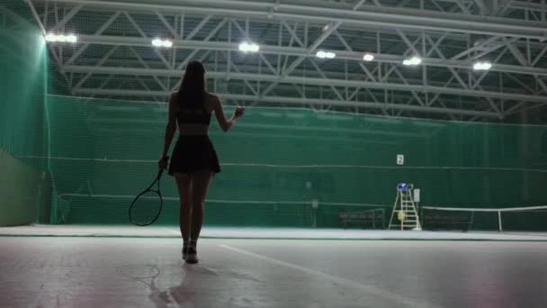 Mujer sexy en pista de tenis cubierta, vista trasera de la dama delgada en ropa deportiva, la celebración de raqueta de tenis — Vídeos de Stock