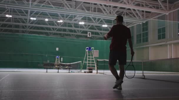 Profesionální mužský tenista s míčkem a raketou na vnitřním hřišti, zadní pohled, sportovec je oblečen — Stock video