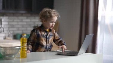 Yakışıklı çocuk evde dizüstü bilgisayar kullanıyor. Hafta sonları tek başına mutfakta durup çizgi film izliyor.