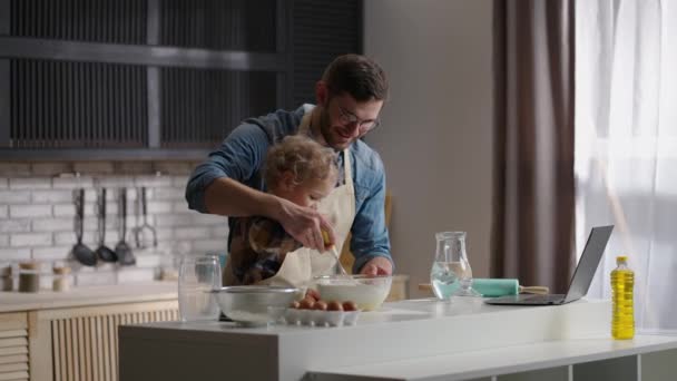 Rustig familie weekend, kleine zoon en vader koken samen deeg in de keuken van het appartement overdag — Stockvideo