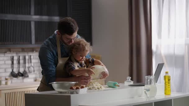 Чоловік і його син готують тісто на домашній кухні, тато вчить свою дитину готувати, проводячи час разом — стокове відео
