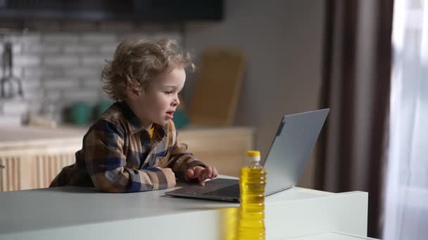 Copil băiat cu laptop pe bucătărie, copil este folosind internetul pentru divertisment și educație, portret mediu — Videoclip de stoc