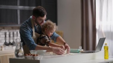 Sevgili babası küçük oğluna yemek yapmayı öğretiyor. Mutfak masasında hamur yoğuruyor. Baba ve oğul.