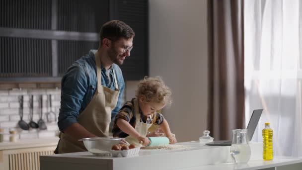 Padre con il suo piccolo figlio stanno cucinando, stendendo pasta sul tavolo della cucina in appartamento moderno — Video Stock