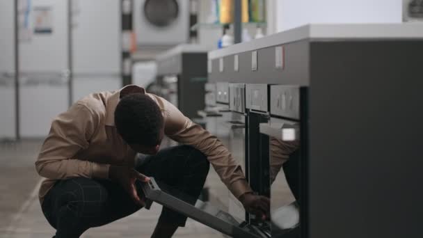 Αφρο-Αμερικανός άντρας ψωνίζει σε κατάστημα οικιακών συσκευών, μαύρος διαλέγει εξοπλισμό για οικιακή κουζίνα — Αρχείο Βίντεο