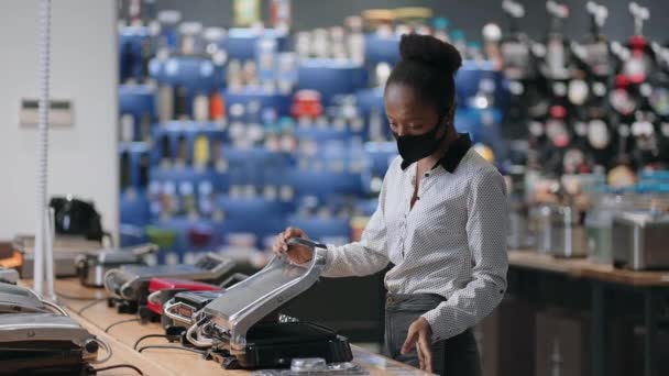 Młoda czarna kobieta czyta informacje na etykiecie i tagu w sklepie AGD, wybierając elektryczne gofrownica do gotowania w domu — Wideo stockowe
