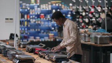 Genç erkek alışverişçi elektrikli ızgara ya da elektrikli waffle ızgarasını ev aletleri mağazasından seçiyor.