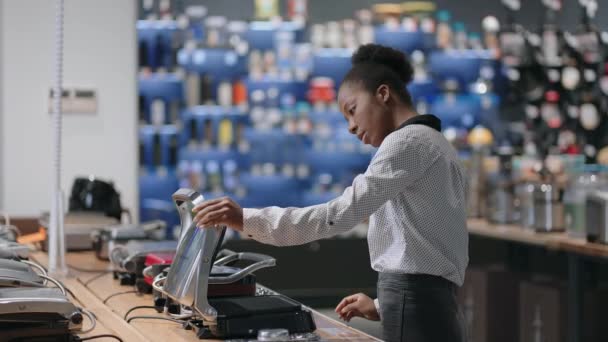 Афроамериканська домогосподарка купує електричний гриль в магазині з сучасною технікою для дому та кухні — стокове відео