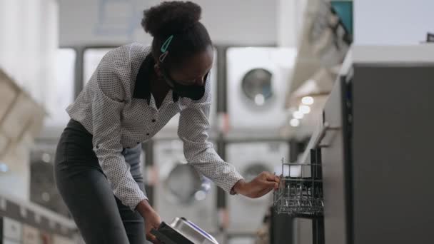 Genç siyah bayan bulaşıkçıyı ev aletleri dükkanından seçiyor, mutfak için ekipman alıyor. — Stok video
