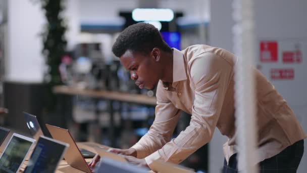 Mladý černý programátor vybírá nový notebook pro práci v obchodě s elektronikou, testovací ukázka — Stock video