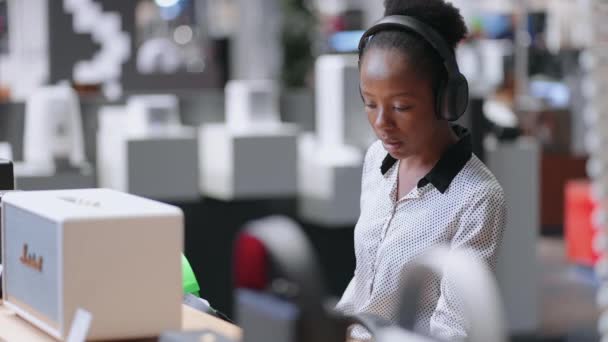 Afro-americká žena se snaží bezdrátové sluchátka v obchodní hale audio vybavení shop, testování nového modelu před nákupem — Stock video