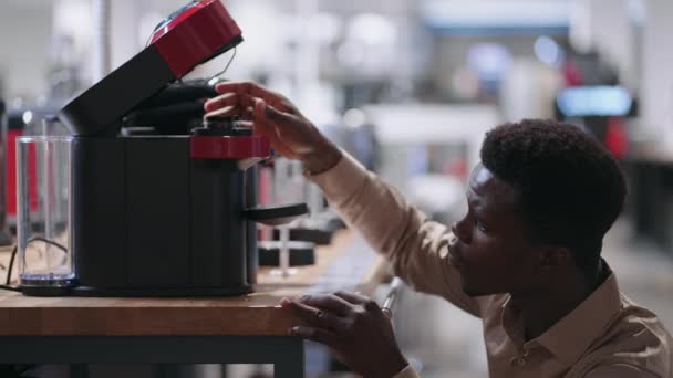 Hombre está viendo la máquina de café moderna en la tienda de electrodomésticos, joven negro está de compras en el centro comercial — Vídeos de Stock