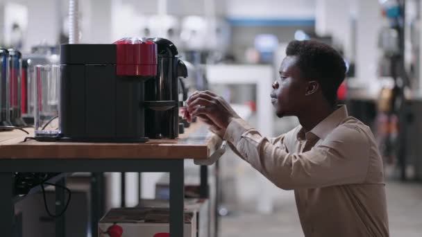 Hombre negro está eligiendo la cafetera automática en la tienda de electrodomésticos, visualización de la muestra de exposición de dispositivo moderno — Vídeos de Stock