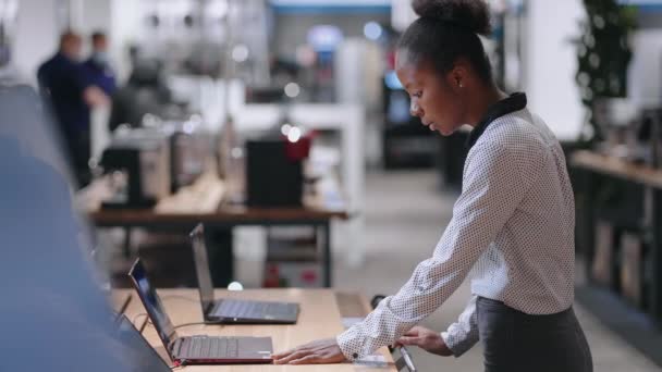 Frau wählt Laptop in Handelshalle des Elektronikgeschäfts, testet neues Modell, zeigt Ausstellungsbeispiel — Stockvideo