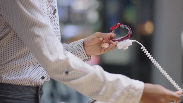 Μαύρη γυναίκα συγκρίνει δύο μοντέλα SmartWatch στο κατάστημα ηλεκτρονικών, κρατώντας δείγματα έκθεση στα χέρια, closeup των χεριών — Αρχείο Βίντεο