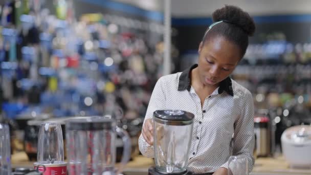 Schwarze Frau kauft Blender im Verbrauchermarkt und sieht sich Ausstellungsbeispiel auf Schaukasten an — Stockvideo