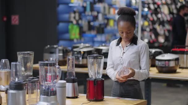 Comprador fêmea está escolhendo liquidificador na loja, vendo amostras de exposição na vitrine, mulher está comprando na loja de aparelhos de cozinha — Vídeo de Stock