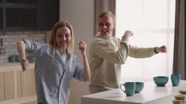 Счастливая веселая пара танцует на кухне во время приготовления пищи вместе. — стоковое видео