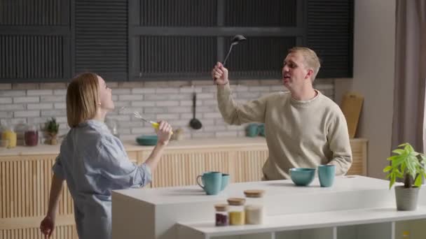 Jovem casal alegre se divertir dançando e cantando enquanto definir a mesa para o café da manhã na cozinha em casa — Vídeo de Stock