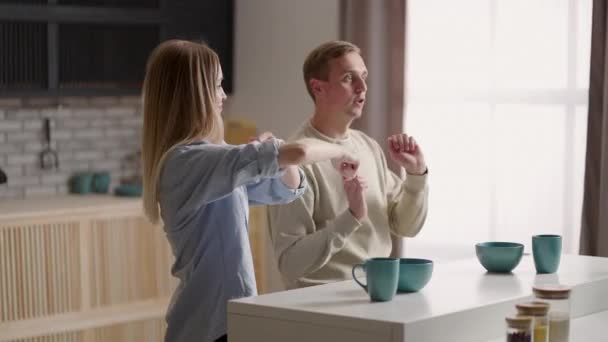 Jong gelukkig actief familie paar dansen samen koken eten thuis, zorgeloos blij man en vrouw hebben plezier koken gezond romantisch diner luisteren naar muziek in de moderne keuken — Stockvideo