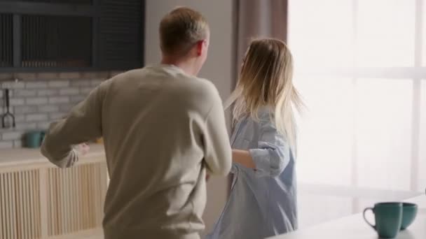 Jóvenes feliz familia activa pareja bailando riendo juntos preparando la comida en casa, sin preocupaciones alegre marido y esposa divirtiéndose cocinar comida romántica saludable cena escuchar música en la cocina moderna — Vídeos de Stock