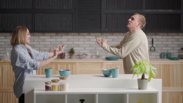 Feliz casal alegre dançando na cozinha enquanto cozinhando juntos. — Vídeo de Stock