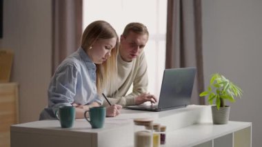 Çiftler kanepede oturur faturalarını öder dizüstü bilgisayar uygulaması kullanır, ev harcamalarını analiz eder, ev tasarruflarını hesaplar, yatırım planlar, ipotek kredisi konsepti yapar.