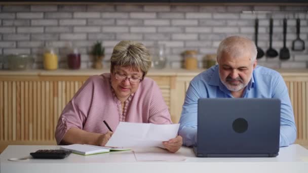 Oudere man en vrouw vullen rapport in laptop thuis, vrouwelijke accountant is het tellen en het geven van gegevens aan collega — Stockvideo