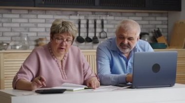 Yaşlı eşler hafta sonunu evde geçiriyor, kadınlar faturaları hesaplıyor ve kocası internette sörf yapıyor.