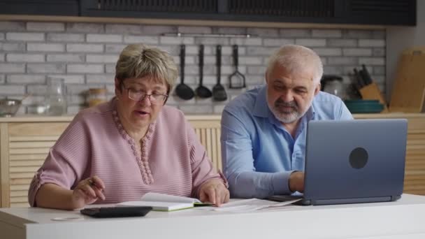 Starsi małżonkowie spędzają weekend w domu, kobieta oblicza rachunki za media, a jej mąż surfuje po Internecie — Wideo stockowe