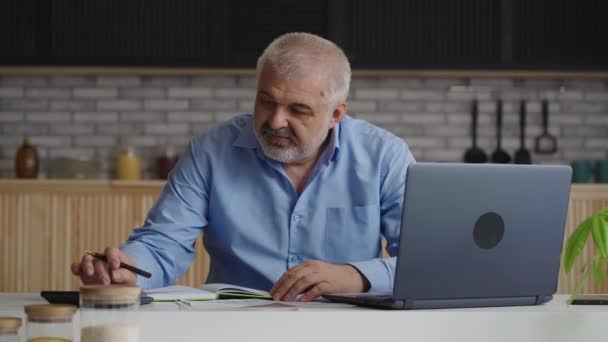 Viejo asesor financiero masculino está trabajando desde casa, contando por calculadora, utilizando el ordenador portátil para hacer informe — Vídeos de Stock