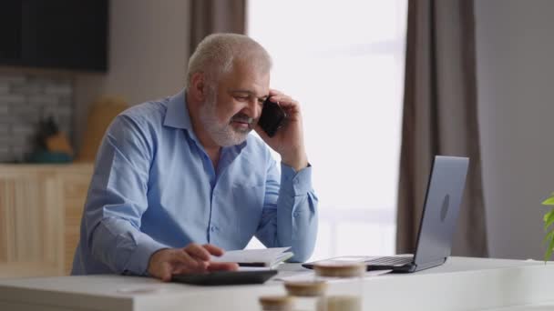 Man revisor arbetar hemifrån, konsultera kund per telefonsamtal, beräkna och svara på frågor distans — Stockvideo