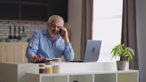 Homme d'affaires âgé appelle par téléphone de la maison, négocier avec des partenaires et des fournisseurs, calculer et discuter des prix — Video