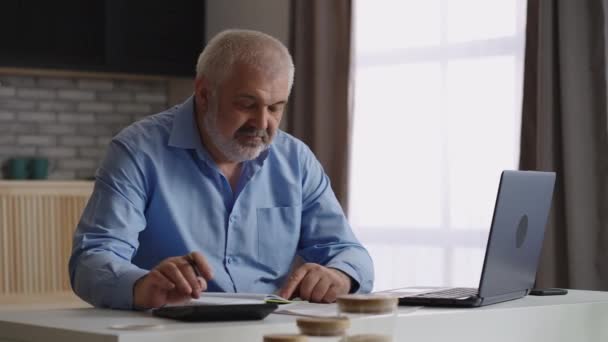 Пожилой человек заполняет отчет в ноутбуке, финансовый специалист или бухгалтер работает в домашнем офисе — стоковое видео