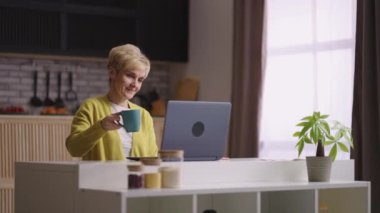 İnternet teknolojisi ve video çağrısı kullanarak uzaktan iletişim kuran yaşlı kadın, arkadaşları ya da ailesi ile çevrimiçi sohbet ediyor ve evde oturuyor.